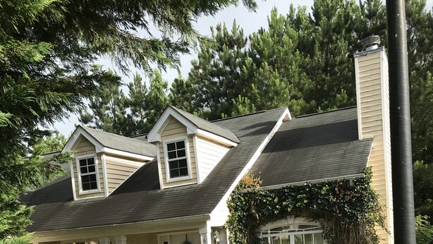 A two-story house with a covered porch, a chimney, and a well-maintained lawn.