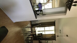 A dining area with a table and chairs, a window with curtains, and a chandelier.