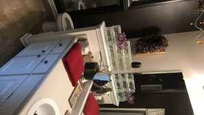 A bathroom with a white sink, red towels, a mirror, and a decorative plant.