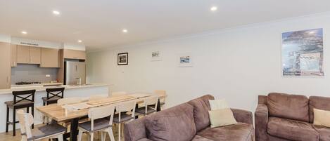 A modern living room with a dining area, a kitchen, and a large painting on the wall.
