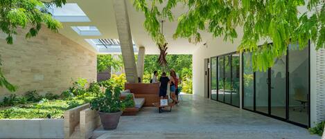 A modern indoor space with a central seating area, glass walls, and greenery.