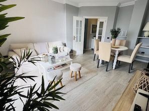 A modern living room with a sofa, coffee table, and dining area.