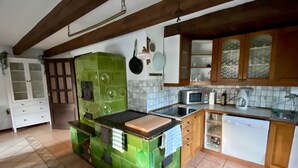 A kitchen with green cabinetry, a central island, a microwave, a dishwasher, and wooden cabinets. - Holiday home Lipno, Slupečná (Lipno nad Vltavou)