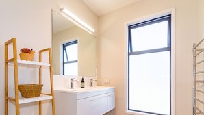 Une salle de bain moderne avec un meuble-lavabo blanc, un grand miroir et une fenêtre.