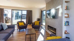 Un salon moderne avec une cheminée, deux fauteuils, un canapé et une table basse.