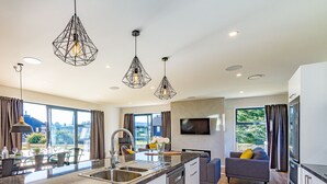 Une cuisine moderne dotée d’un îlot central, d’appareils électroménagers en acier inoxydable et de luminaires suspendus.