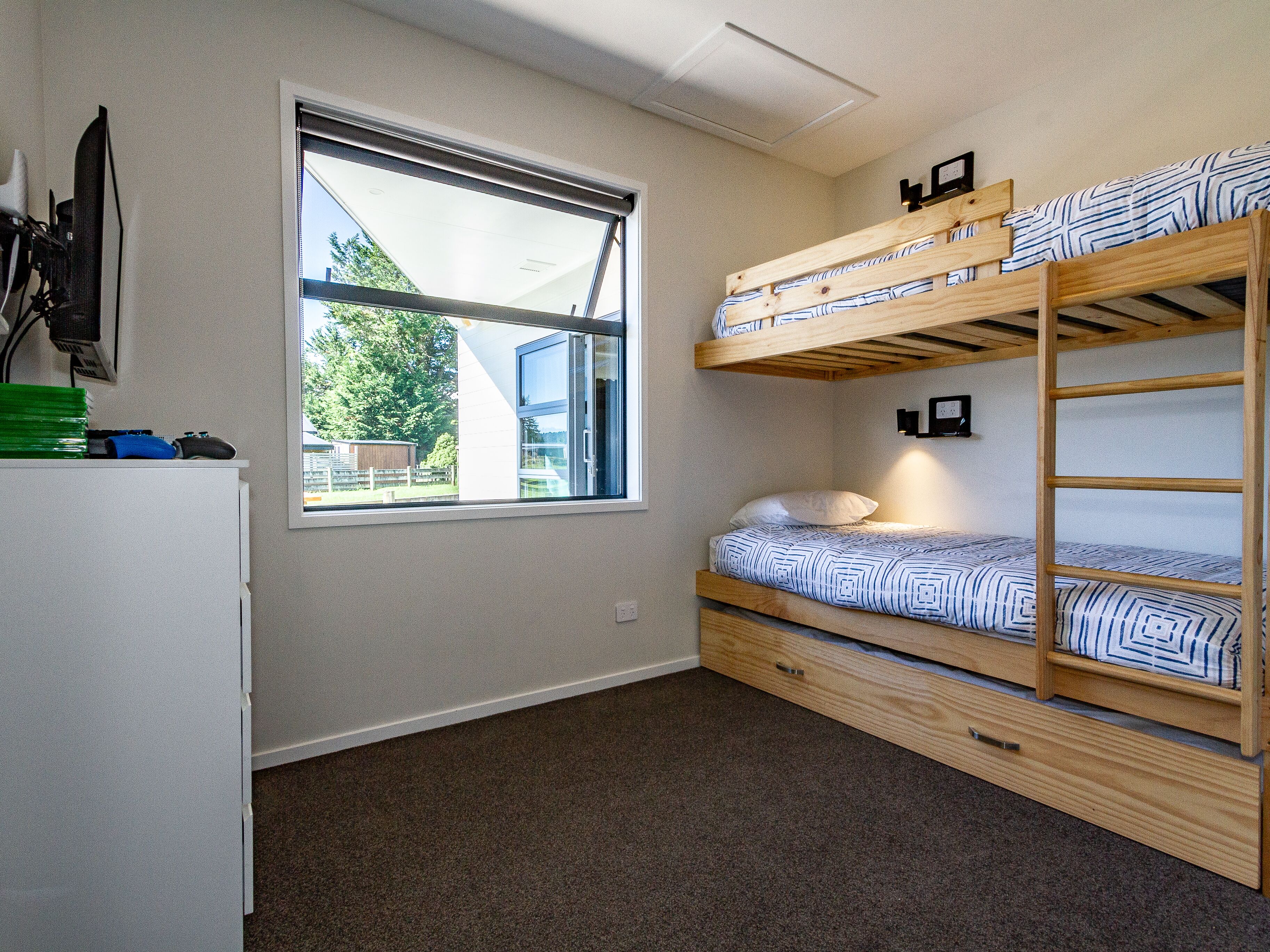 Dormitorio con literas, una ventana, un escritorio y una silla.