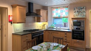 A modern kitchen with wooden cabinets, a gas stove, an oven, and a microwave.