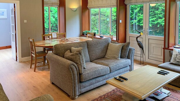 A cozy living room with a sofa, coffee table, and dining area.