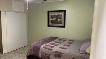 Een slaapkamer met een bed, een plafondventilator, een lijst met een afbeelding aan de muur en een kledingkast.