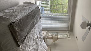 A bedroom with a bed, a window with blinds, a wall-mounted lamp, and a radiator. - Close to beautiful beach (Avalon)