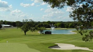 A golf course with a pond, sand bunkers, and a small building near the water. - Salado Cottage Retreat near Downtown (Salado)