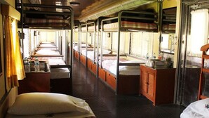 Een treinwagon met slaapplekken, een kleine kitchenette en een raam met gordijnen.
