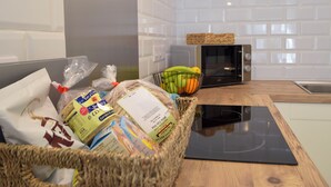 A kitchen with a microwave, a basket of fruits, and packaged food items on the counter.