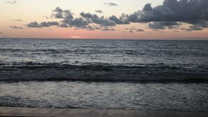 Una platja amb onades i un capvespre al fons.