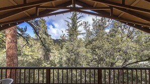 A covered outdoor area with a wooden deck, a table, and chairs. - Treetop Getaway in the Ponderosa Pines (Idyllwild-Pine Cove)