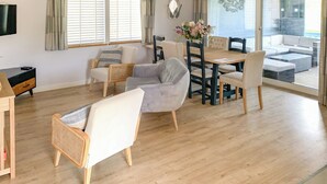 Un vaste espace de vie doté d’un plancher en bois, d’une table à manger avec des chaises, d’un canapé et d’un téléviseur fixé au mur.