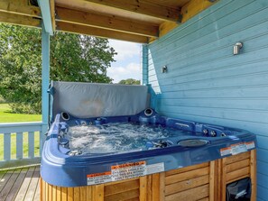 Uma banheira de hidromassagem com deck de madeira e parede azul ao fundo.