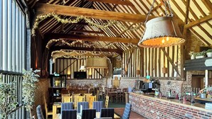 Un espace de restauration intérieur avec des tables et des chaises en bois, un mur en briques et des luminaires suspendus.