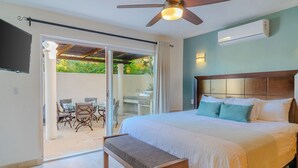 Un dormitorio con cama, banca, ventilador de techo y aire acondicionado.