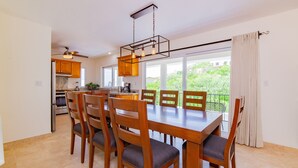 Una cocina moderna con armarios de madera, una isla grande y un comedor con mesa y sillas de madera.