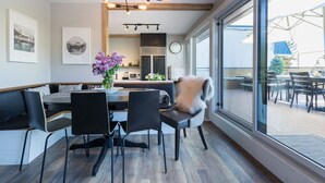 Uma área de jantar moderna com uma mesa grande, cadeiras pretas e um lustre decorativo.