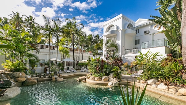 Un resort con piscina rodeada de palmeras y sillas de descanso.