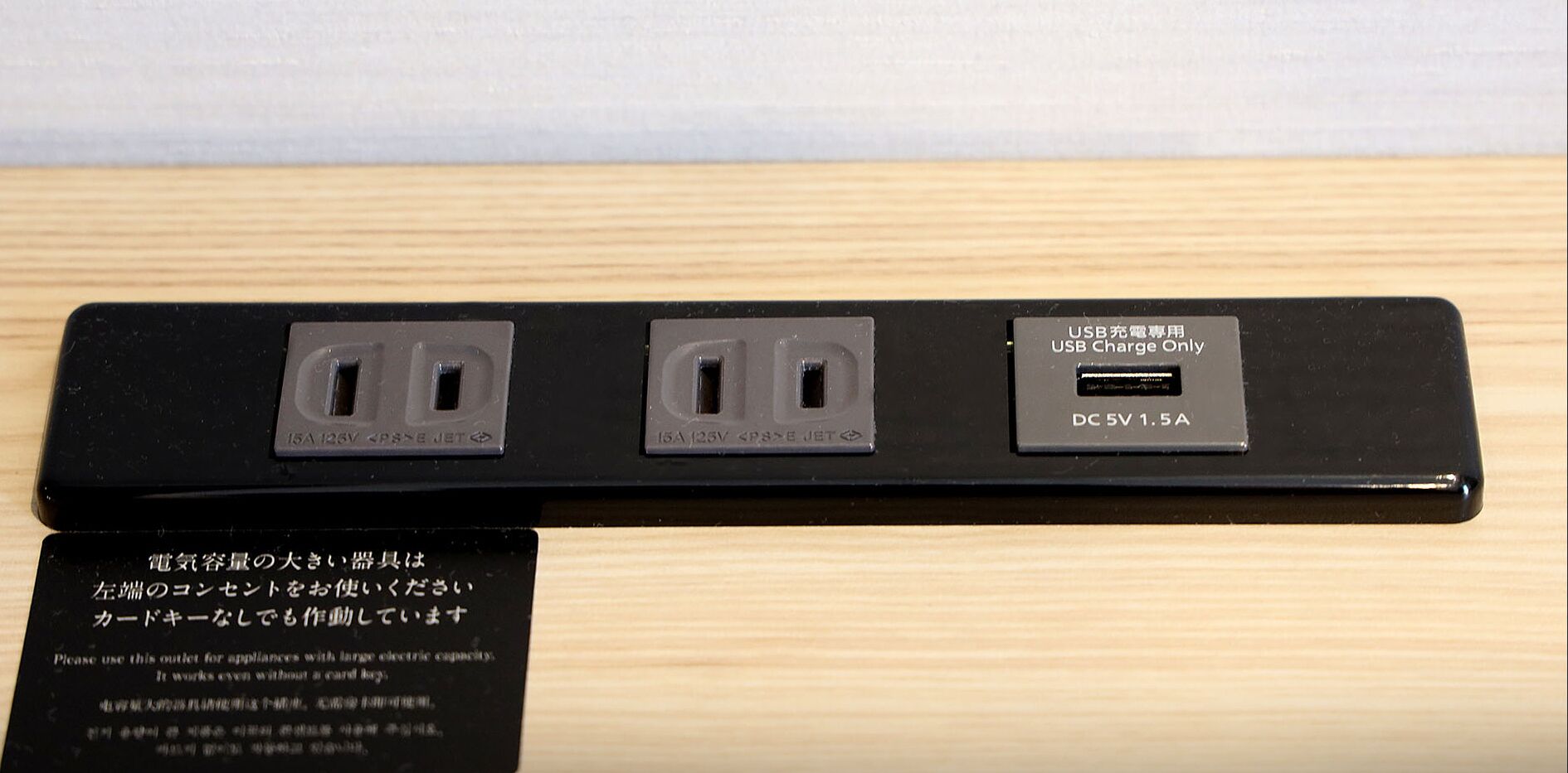 Eine schwarze Mehrfachsteckdose mit drei Steckdosen und einem USB-Anschluss, beschriftet mit 15A, 125V und DC 5V, 1,5A.
