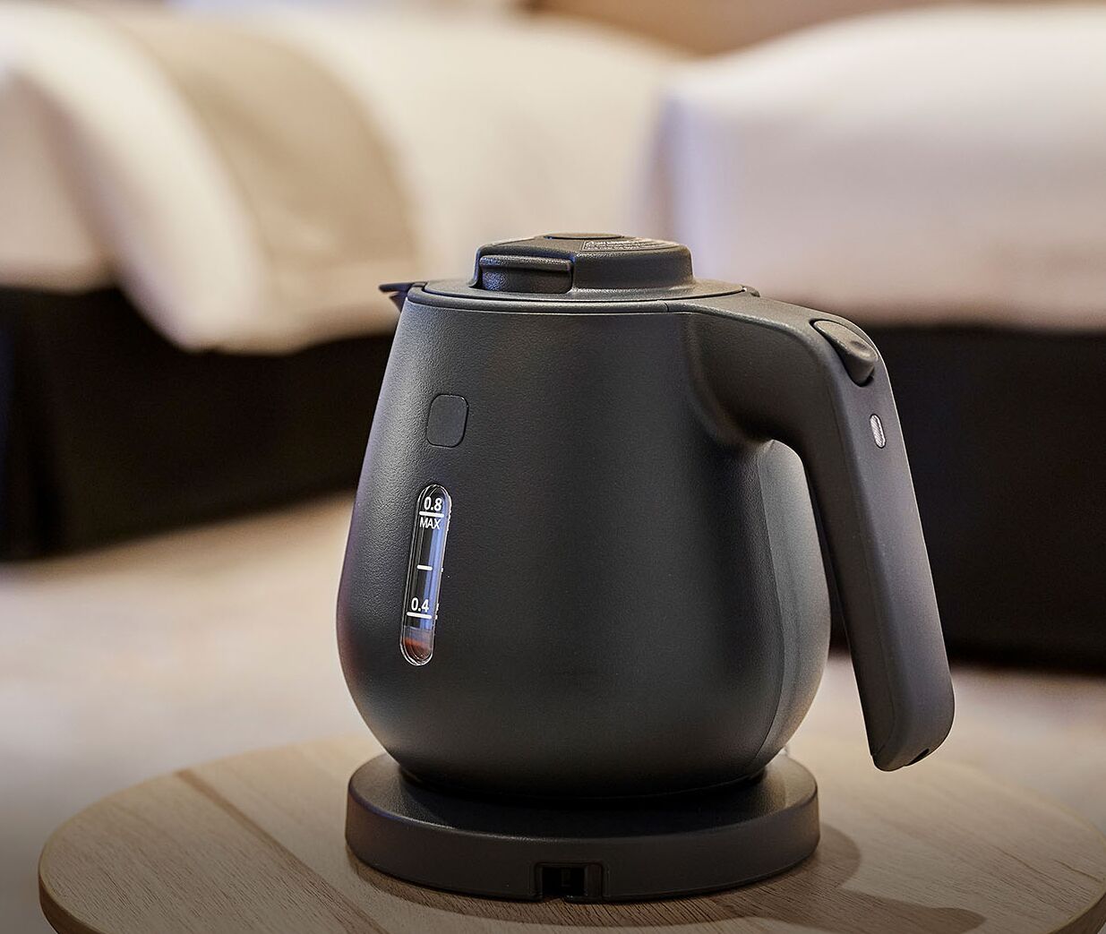 A modern electric kettle on a wooden coaster.