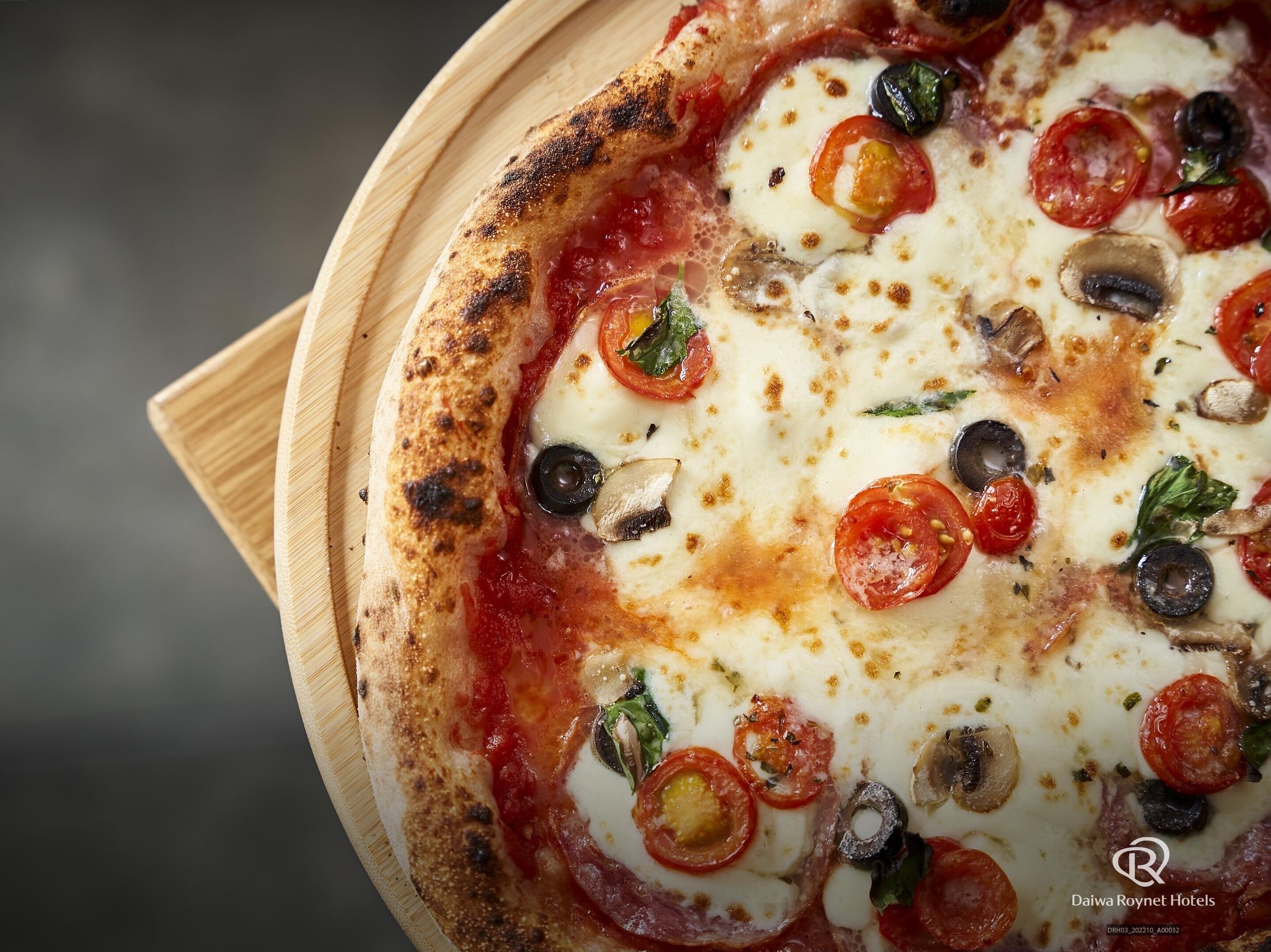 Une pizza garnie et un plateau de service en bois.
