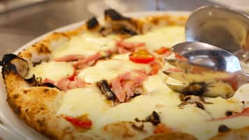 Une pizza garnie, avec une cuillère posée sur une assiette.