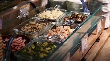Un bufé con diversas opciones de comida, incluyendo carnes, ensaladas y otros platos, exhibidos en recipientes de vidrio.