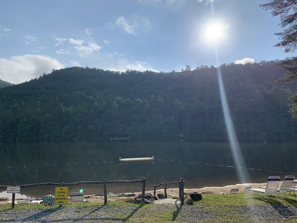 A lakeside view with a wooden dock, a no boating and fishing sign, and a row of sun loungers.