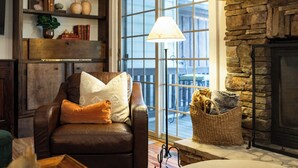 Una sala de estar acogedora con un sillón de cuero, una chimenea, un ventanal grande y una lámpara de pie.