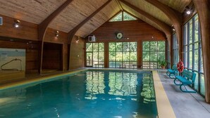 Una piscina interior con vigas de madera, ventanas amplias y bancos a lo largo de la pared.