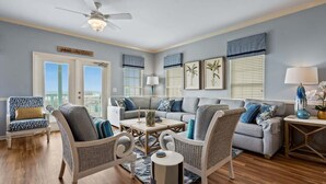 Un salon comprenant un ensemble de canapés, deux fauteuils, une table basse et un ventilateur de plafond.