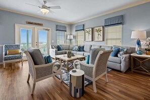 A living room with a sofa set, two armchairs, a coffee table, and a ceiling fan. - Stunning views at this large oceanfront home w/pool and game room ready for family fun! (North Myrtle Beach)