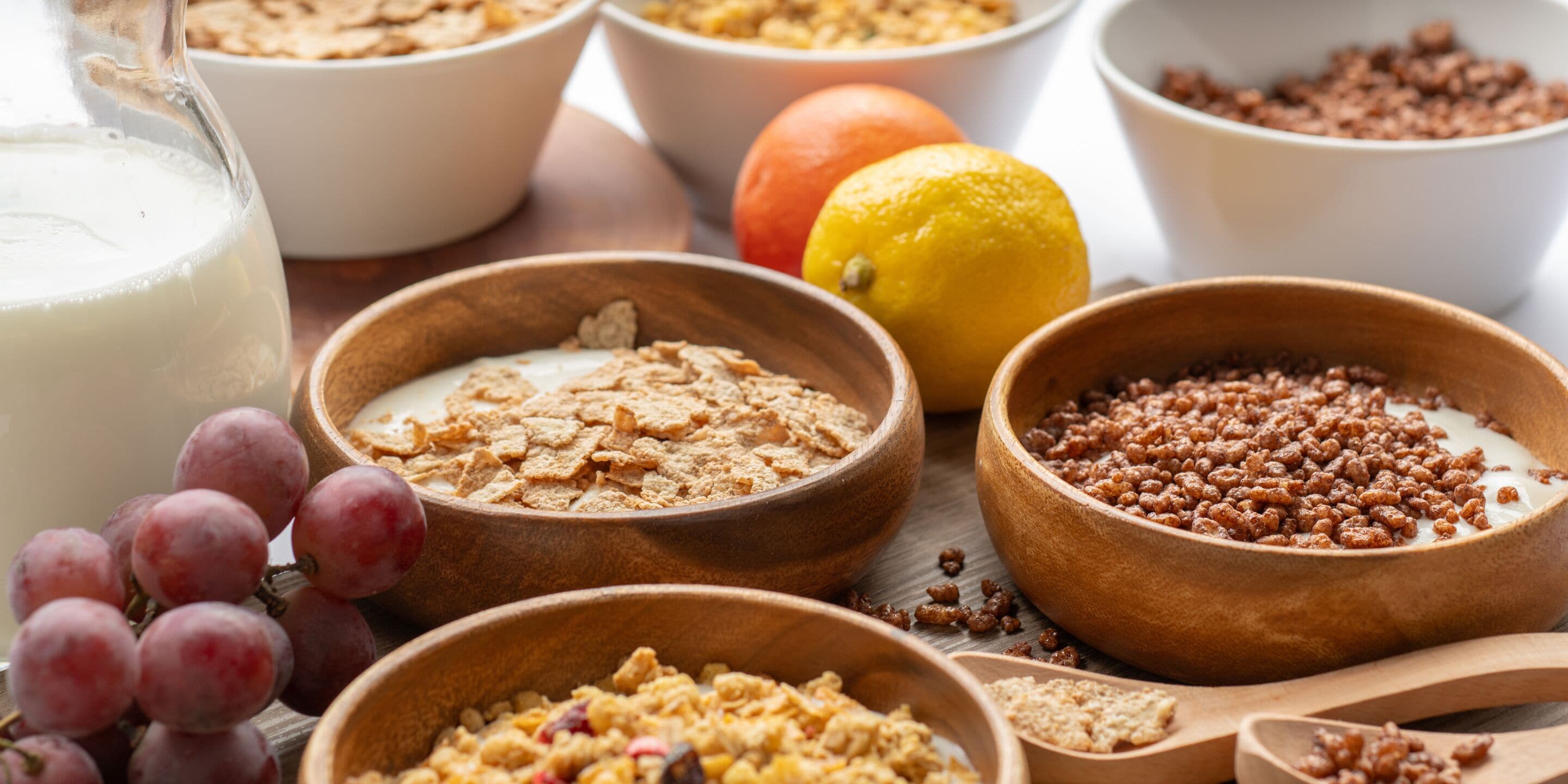 Bowls of cereal and milk on a table.