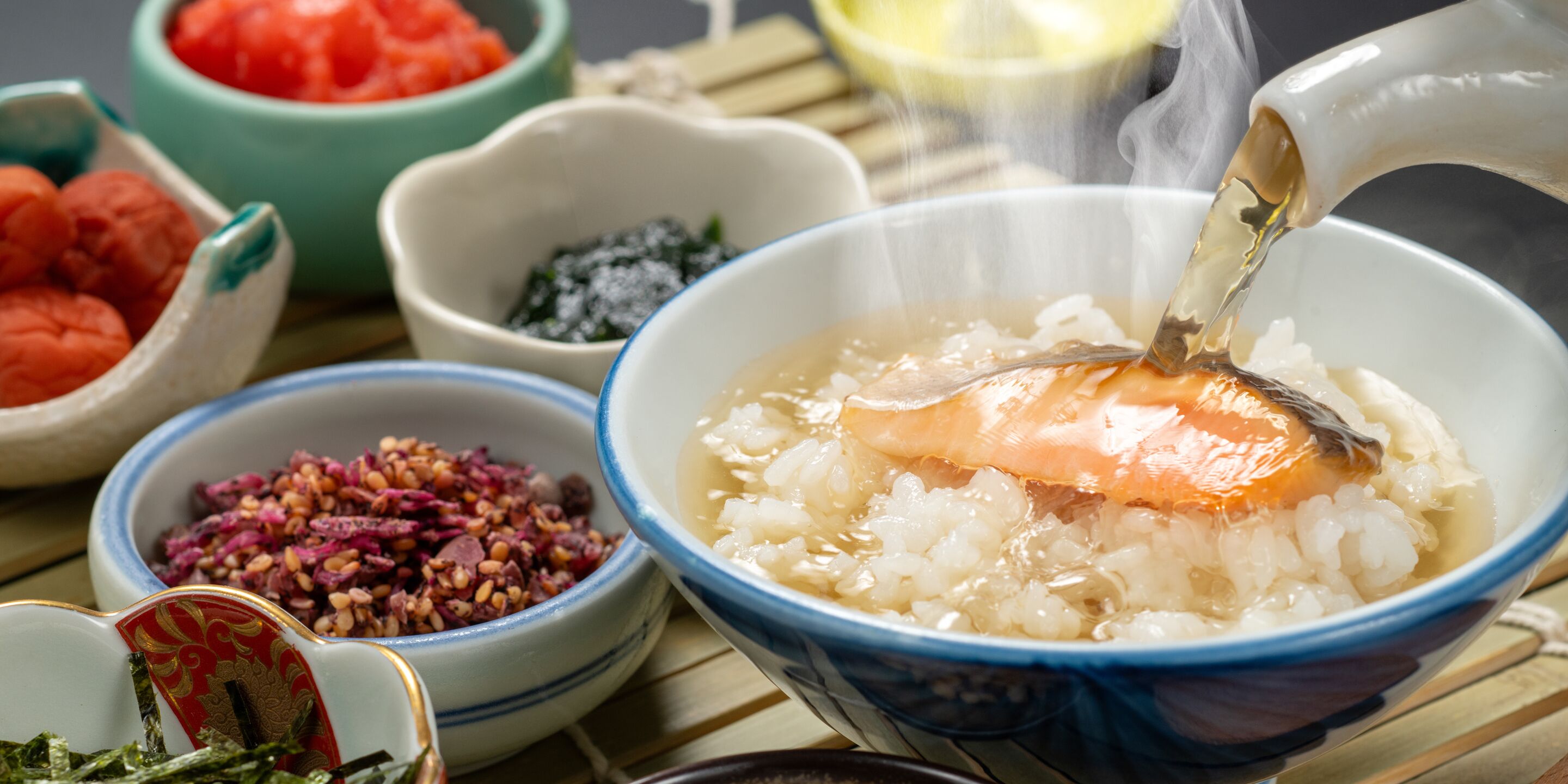 A bowl of rice with salmon and a spoonful of sauce being poured into it.