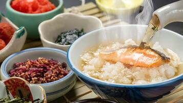 A bowl of rice with salmon and a spoonful of sauce being poured into it.