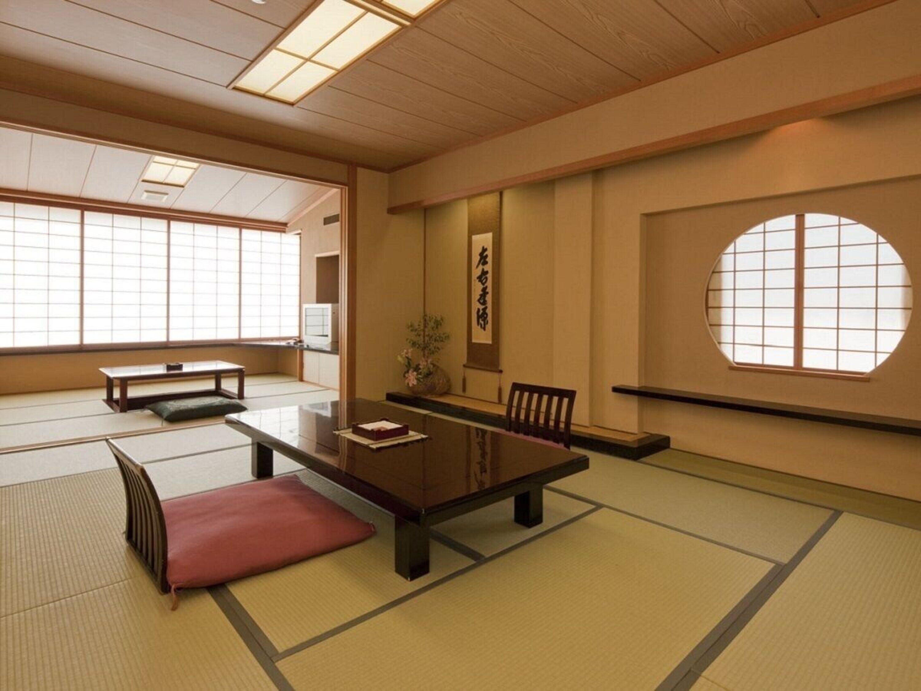 A traditional Japanese tatami room with tatami mats, a low table, a cushion, and a sliding door.
