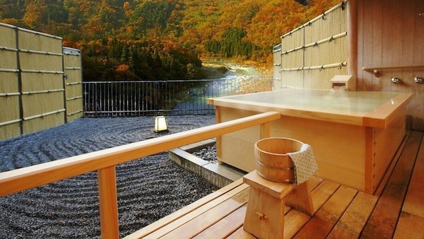 Un onsen japonés tradicional con bancos de madera y un baño de aguas termales.