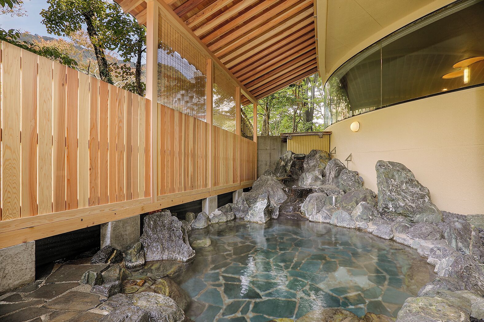 A traditional Japanese onsen with a wooden deck and a stone hot spring area.