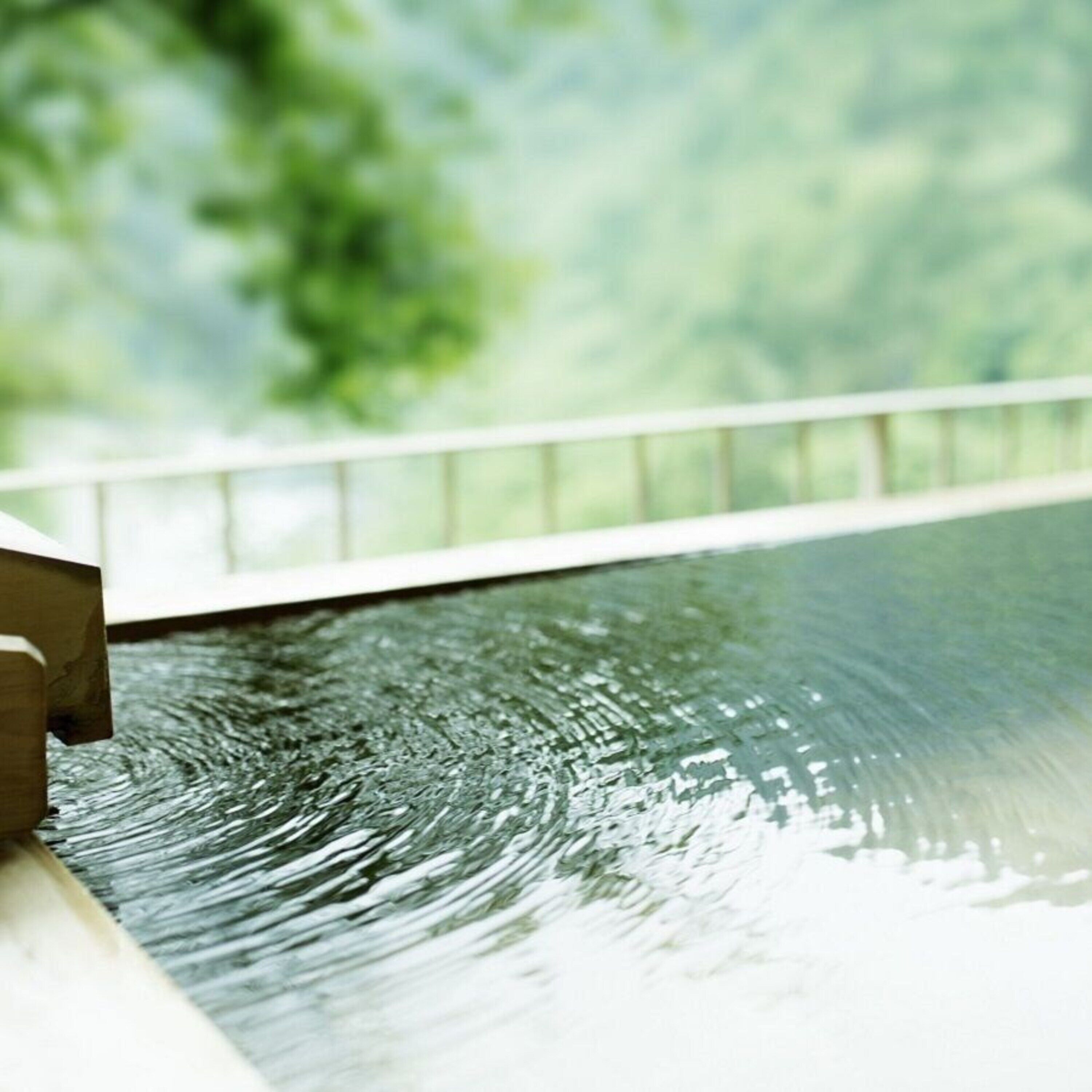 Une piscine avec une terrasse en bois et une rambarde.