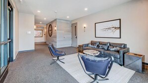 Ein modernes Wohnzimmer mit einer Couch, zwei Sesseln, einem Couchtisch und einem Wanddekor.