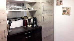A modern kitchen with wooden cabinetry, a countertop with kitchen appliances, and a shelf with glassware. - Apartment with garden in prime location (Tobadill)