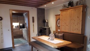 A cozy kitchen with a wooden bench, a dining table, and a clock on the wall. - Apartment with garden in prime location (Tobadill)