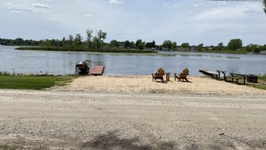 Uma área à beira do lago com um píer, cadeiras e mesas de piquenique.