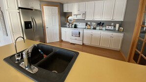 Uma cozinha moderna com armários brancos, eletrodomésticos de aço inoxidável e uma pia preta.