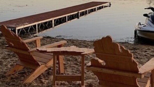 Um cenário à beira do lago, com cadeiras Adirondack de madeira e um píer que se estende na água.